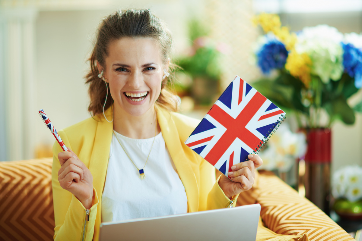 happy trendy student with laptop showing UK flag notebook